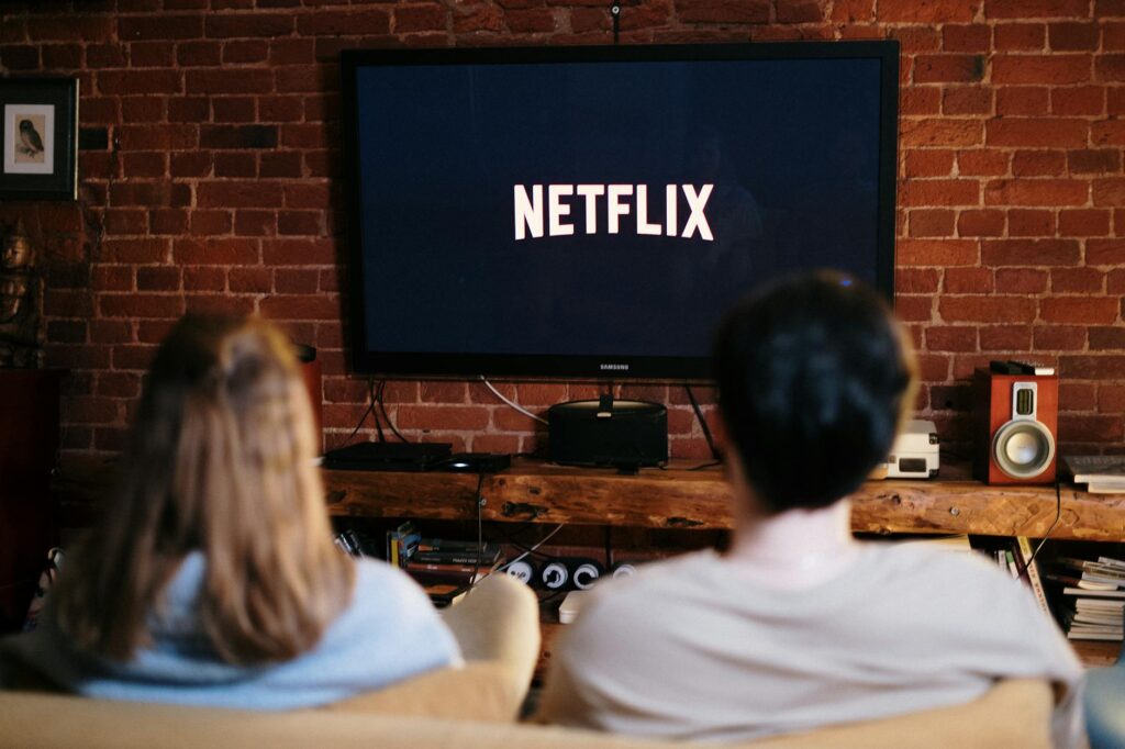 man and woman sitting on a couch in front of a television